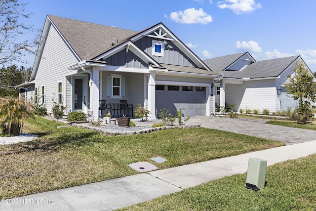 view of front of house with a garage, covered porch, decorative driveway, board and batten siding, and a front yard