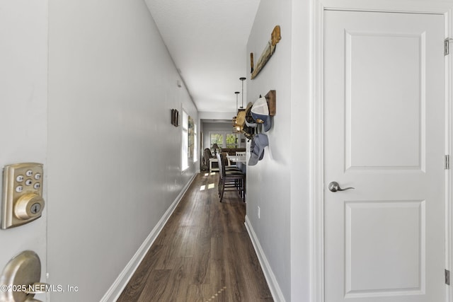 corridor featuring dark wood-type flooring and baseboards