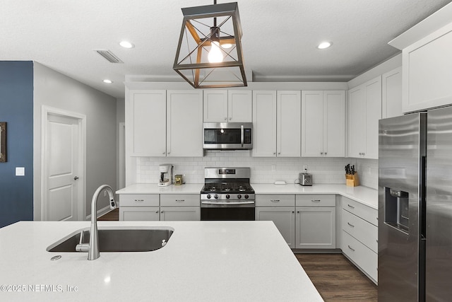 kitchen with a sink, visible vents, light countertops, appliances with stainless steel finishes, and tasteful backsplash