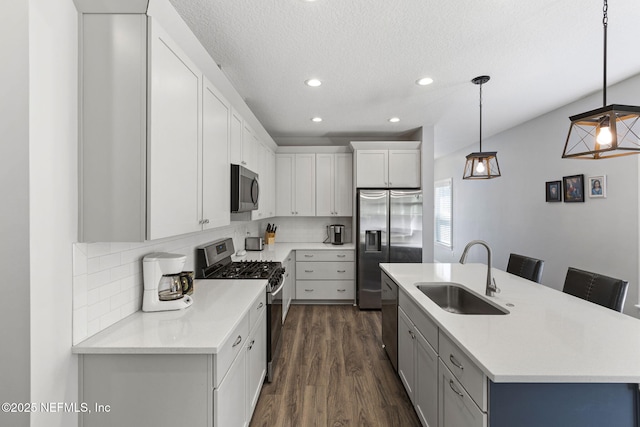 kitchen featuring appliances with stainless steel finishes, dark wood-type flooring, a sink, light countertops, and backsplash