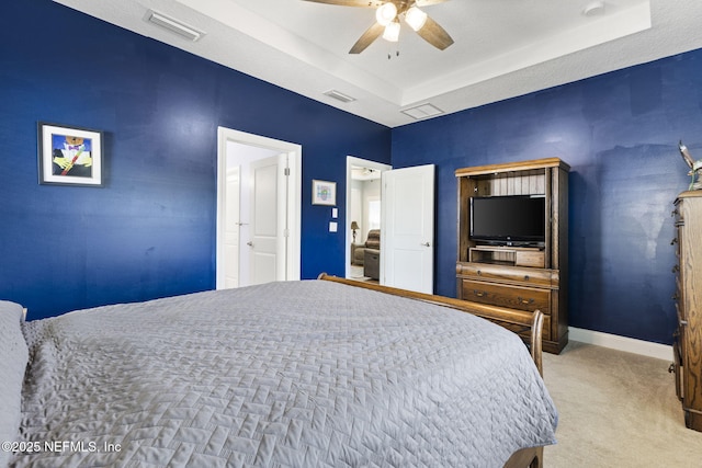 carpeted bedroom featuring a raised ceiling, visible vents, and baseboards