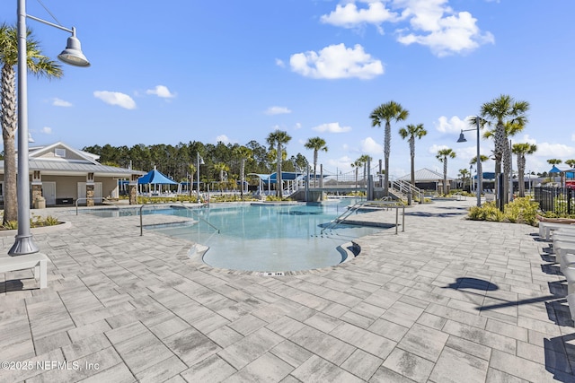 pool with a patio, a water slide, and fence