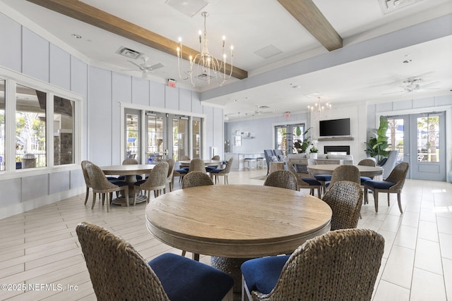 dining area featuring french doors, a decorative wall, a healthy amount of sunlight, beamed ceiling, and ceiling fan with notable chandelier