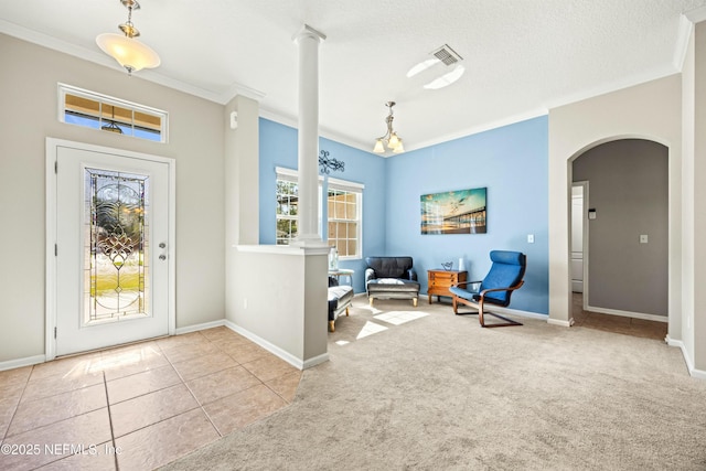 carpeted foyer entrance featuring arched walkways, ornamental molding, visible vents, and baseboards