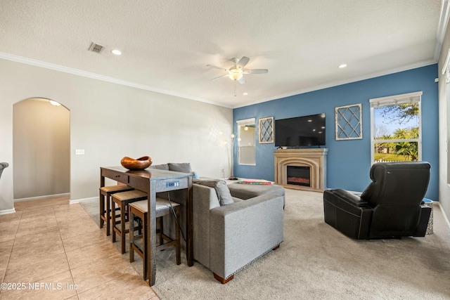 living area with light tile patterned floors, arched walkways, a textured ceiling, and ornamental molding