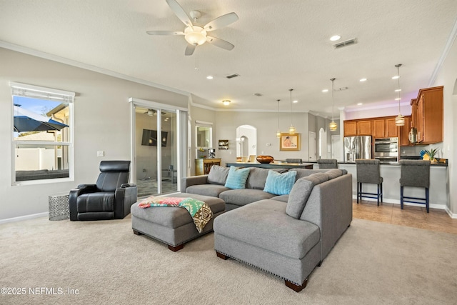 living area featuring visible vents, arched walkways, crown molding, and light colored carpet