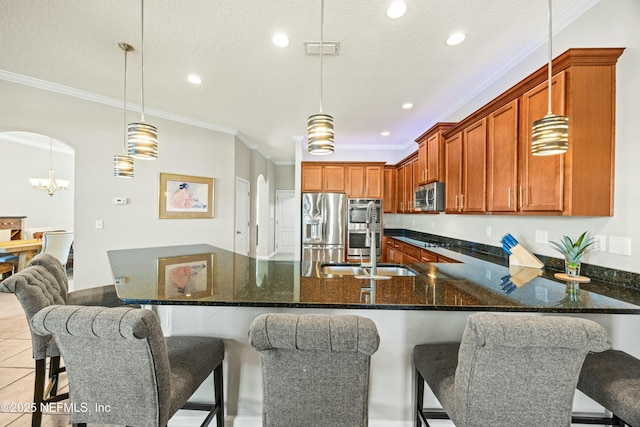 kitchen featuring appliances with stainless steel finishes, arched walkways, and ornamental molding