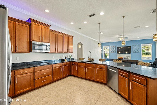 kitchen featuring appliances with stainless steel finishes, brown cabinetry, a sink, and visible vents