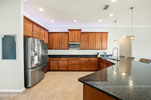 kitchen featuring brown cabinets, visible vents, stainless steel appliances, and a sink