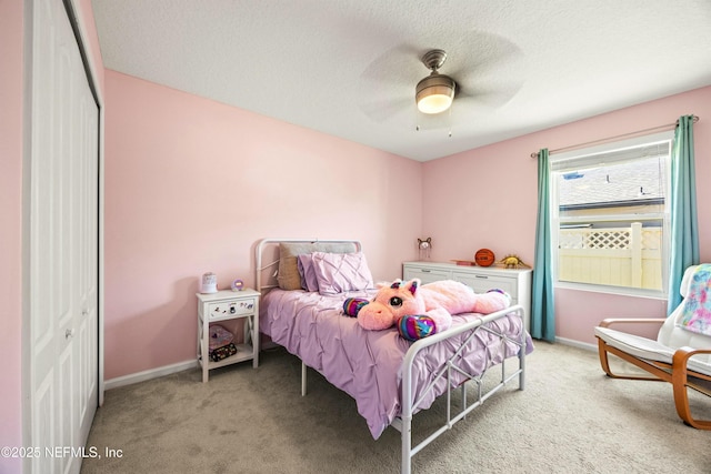 bedroom featuring a textured ceiling, baseboards, a closet, and light colored carpet