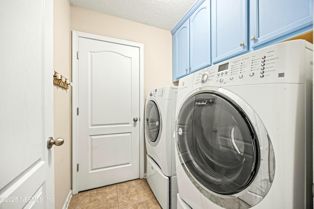 laundry room with cabinet space, washing machine and dryer, light tile patterned floors, and a textured ceiling