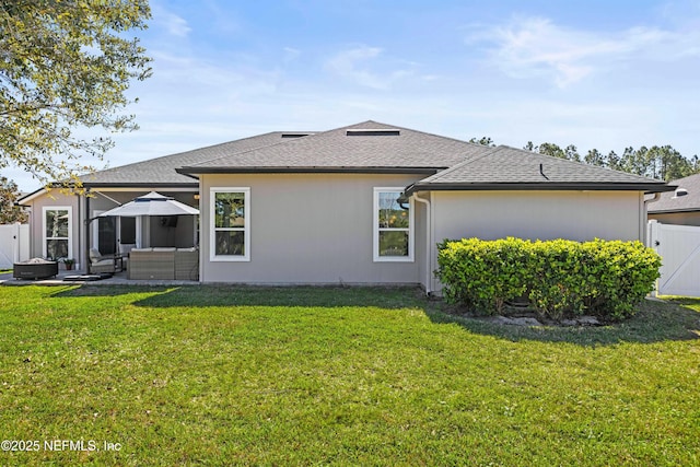 rear view of house featuring roof with shingles, a yard, outdoor lounge area, a patio area, and fence