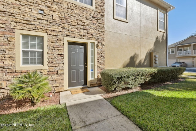 7157 Deerfoot Point Cir Unit 10-2, Jacksonville, FL 32256 - doorway to property featuring stone siding, a yard, and stucco siding