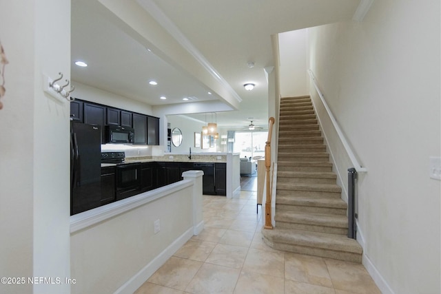 interior space featuring a peninsula, light countertops, dark cabinetry, black appliances, and light tile patterned flooring