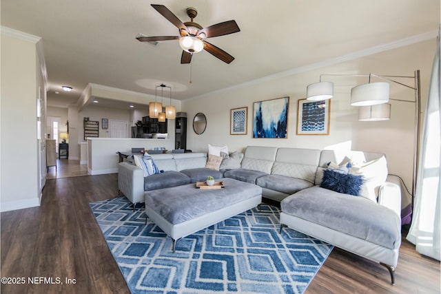 living area with baseboards, ceiling fan, wood finished floors, and crown molding