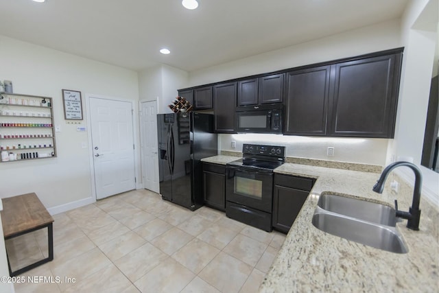 kitchen featuring recessed lighting, a sink, baseboards, light stone countertops, and black appliances