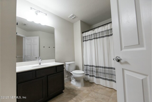 bathroom with visible vents, vanity, toilet, and a textured ceiling