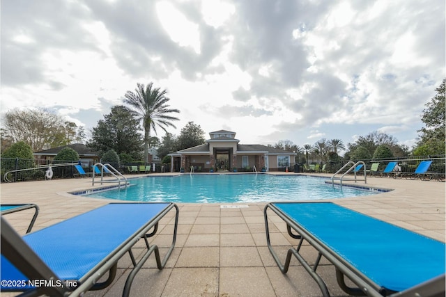 community pool with a patio area and fence