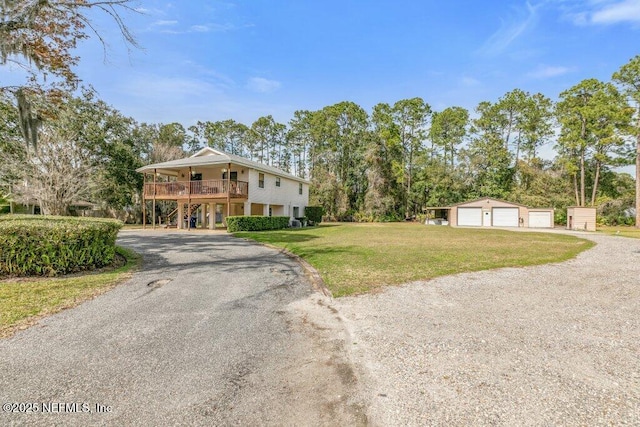 view of front of house with driveway, a detached garage, an outbuilding, and a front yard