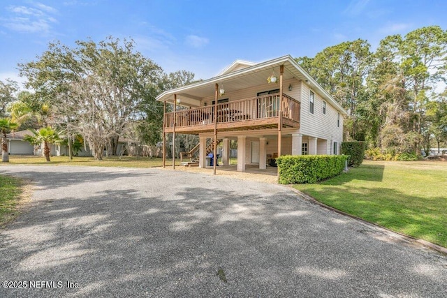 view of front of home featuring a front yard, driveway, stairway, and a wooden deck