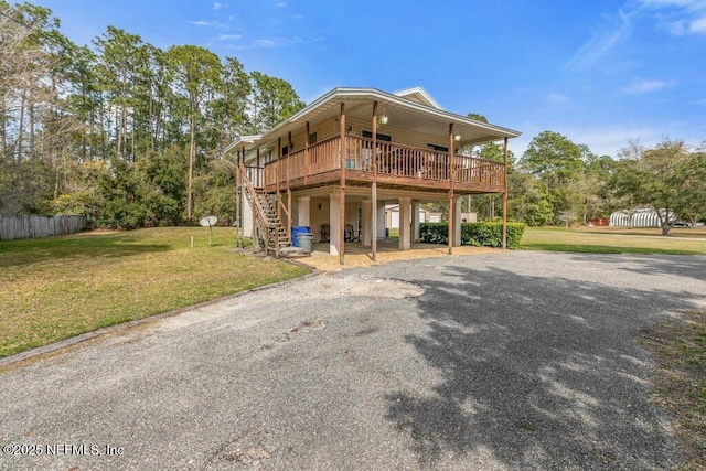 view of front of home featuring fence, a carport, driveway, a front lawn, and stairs