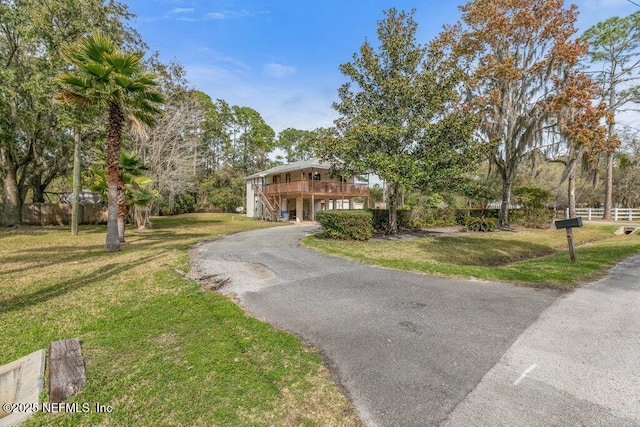 view of front of house with a deck, aphalt driveway, and a front yard