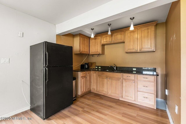 kitchen with light wood-style flooring, a sink, freestanding refrigerator, and baseboards