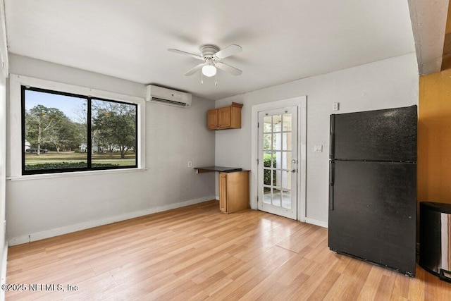 kitchen featuring a wall mounted AC, light wood-style flooring, a wealth of natural light, and freestanding refrigerator