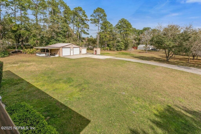 view of yard featuring a garage, driveway, and an outdoor structure