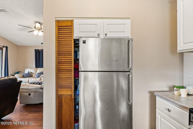 kitchen with white cabinets, ceiling fan, open floor plan, freestanding refrigerator, and light countertops