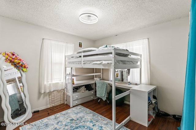 bedroom featuring a textured ceiling, baseboards, and wood finished floors