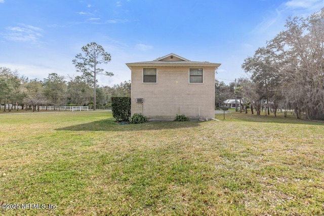 view of side of home featuring a lawn and fence