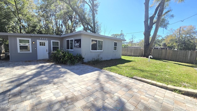 view of front of home with a patio area, fence, and a front lawn