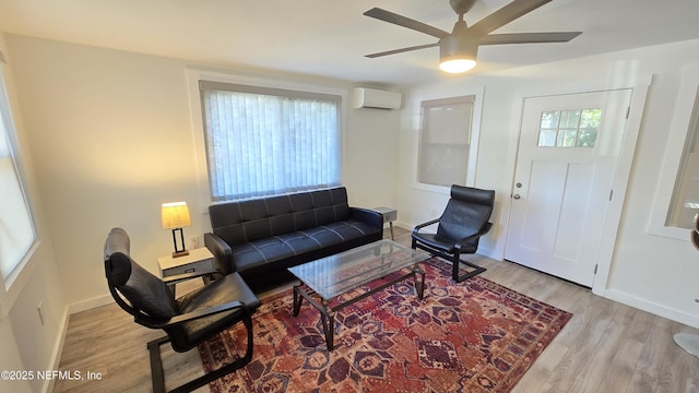 living area with ceiling fan, light wood-style flooring, baseboards, and a wall mounted AC