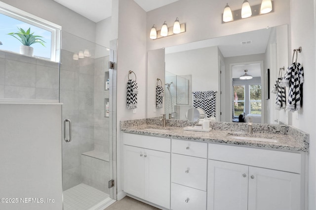 ensuite bathroom with double vanity, a stall shower, and a sink