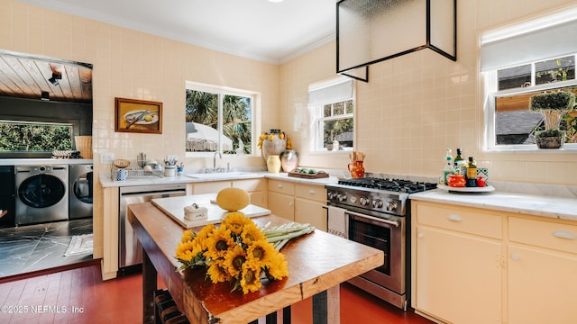 kitchen featuring crown molding, stainless steel appliances, light countertops, a sink, and independent washer and dryer