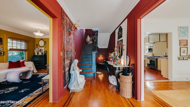 hallway with stairs, crown molding, and wood finished floors