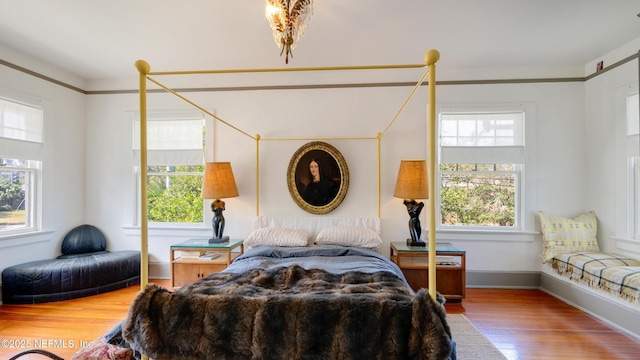 bedroom with crown molding, wood finished floors, and baseboards