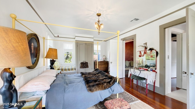 bedroom featuring a chandelier, visible vents, and wood finished floors