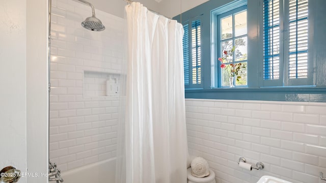 full bath featuring shower / tub combo, tile walls, and wainscoting