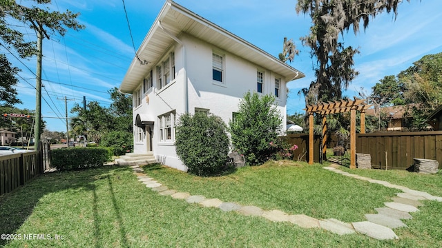 view of side of home with a yard, fence, and stucco siding