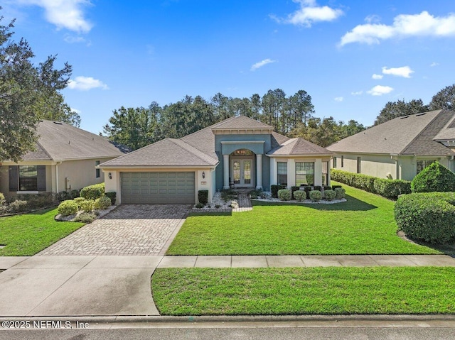 mediterranean / spanish home featuring stucco siding, a front lawn, driveway, french doors, and a garage