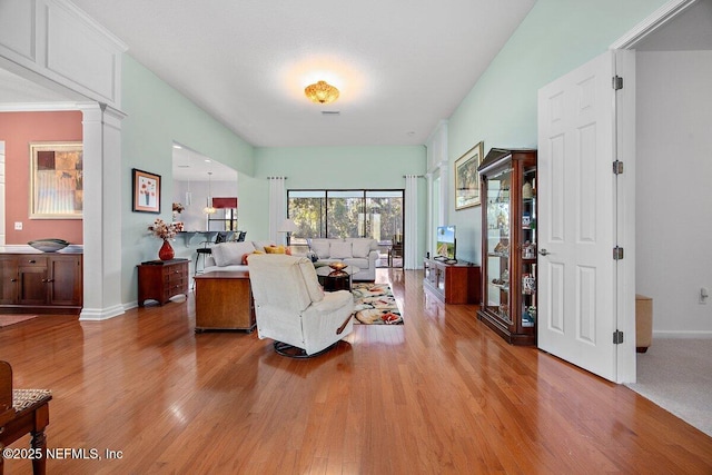 living room with baseboards, light wood-style flooring, and ornate columns