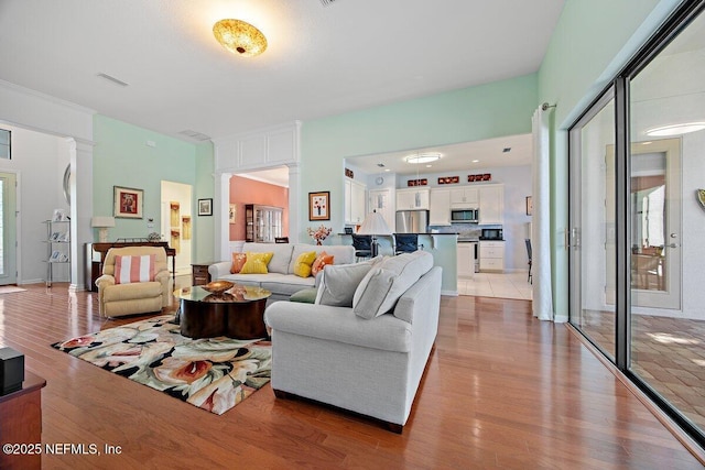 living area featuring decorative columns and light wood-style flooring