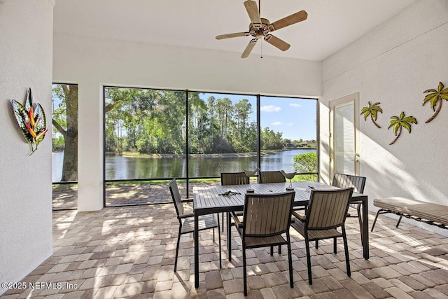 sunroom with ceiling fan and a water view