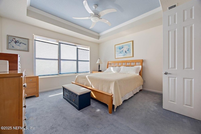 carpeted bedroom with visible vents, baseboards, a raised ceiling, and crown molding