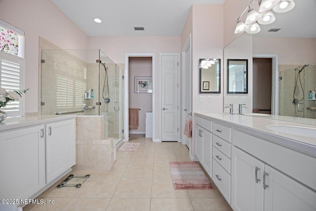 full bathroom with double vanity, a stall shower, visible vents, tile patterned flooring, and a sink