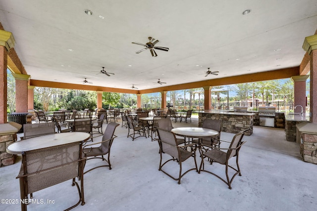 view of patio with outdoor dining area, an outdoor kitchen, a sink, and a ceiling fan