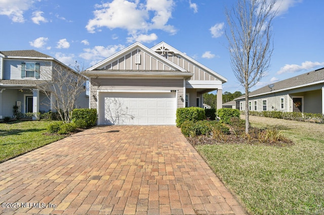 craftsman house featuring board and batten siding, a front yard, decorative driveway, and an attached garage