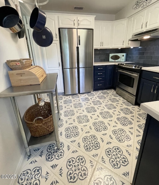 kitchen featuring tasteful backsplash, light countertops, appliances with stainless steel finishes, white cabinets, and under cabinet range hood